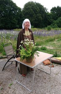 Woman in Viking dress standing behind a table with herbs on it
