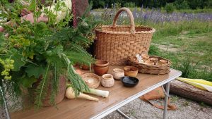 A woven basket, wooden cups and vegetables on a table